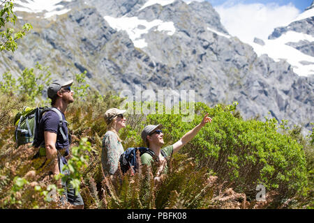 New Zealand aka Aotearoa, South Island, Mt Aspiring National Park, group of friends hiking in bush, with scenic mountain backdrop. Model released. Stock Photo