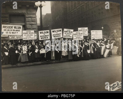 . [Suffragists Protest Woodrow Wilson's Opposition to Woman Suffrage, October 1916]. Summary: Photograph of women suffrage activists wearing suffrage sashes demonstrating with signs at city street corner. Signs read 'President Wilson How Long Do You Advise Us to Wait?', 'Vote Against Wilson He Opposes National Suffrage', 'Wilson is Against Women,' and 'Why Does Wilson Seek Votes From Women When He Opposes Votes For Women.' Police on horseback and on foot far right.. 1916 [Oct. 20] 1582 Suffragists Protest October 1916 276015v Stock Photo