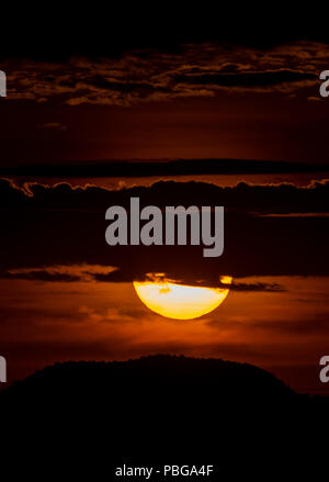 Detail of the sun hiding behind the hill of a hill and the clouds, during the sunset in the west of Hermosillo. The capital of Sonora is one of the hottest in the country. High temperatures. Centigrades Twilight. Solar system. (Photo: Luis Gutiérrez / NortePhoto.com) Stock Photo