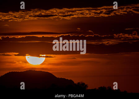 Detail of the sun hiding behind the hill of a hill and the clouds, during the sunset in the west of Hermosillo. The capital of Sonora is one of the hottest in the country. High temperatures. Centigrades Twilight. Solar system. (Photo: Luis Gutiérrez / NortePhoto.com) Stock Photo