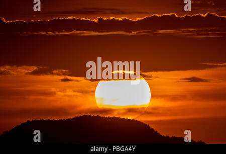 Detail of the sun hiding behind the hill of a hill and the clouds, during the sunset in the west of Hermosillo. The capital of Sonora is one of the hottest in the country. High temperatures. Centigrades Twilight. Solar system. (Photo: Luis Gutiérrez / NortePhoto.com) Stock Photo