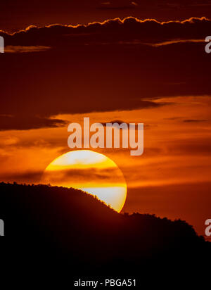 Detail of the sun hiding behind the hill of a hill and the clouds, during the sunset in the west of Hermosillo. The capital of Sonora is one of the hottest in the country. High temperatures. Centigrades Twilight. Solar system. (Photo: Luis Gutiérrez / NortePhoto.com) Stock Photo