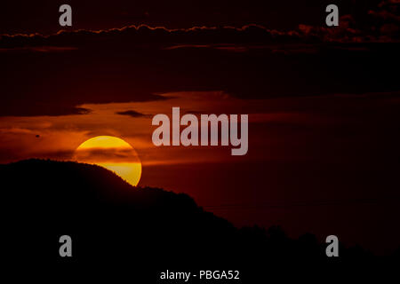 Detail of the sun hiding behind the hill of a hill and the clouds, during the sunset in the west of Hermosillo. The capital of Sonora is one of the hottest in the country. High temperatures. Centigrades Twilight. Solar system. (Photo: Luis Gutiérrez / NortePhoto.com) Stock Photo