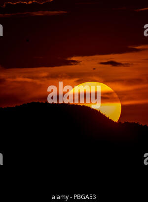 Detail of the sun hiding behind the hill of a hill and the clouds, during the sunset in the west of Hermosillo. The capital of Sonora is one of the hottest in the country. High temperatures. Centigrades Twilight. Solar system. (Photo: Luis Gutiérrez / NortePhoto.com) Stock Photo