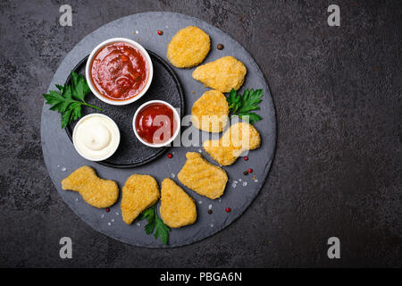 Fried crispy chicken nuggets with popular sauces on a black background, copy space Stock Photo
