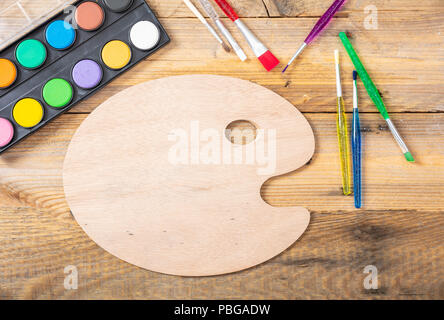 Watercolors, brushes and artist paint palette on wooden background, space for text, top view Stock Photo
