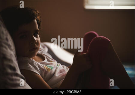 Morning scene, family life, wake up time, portrait of a small girl, laying on bed and watching to camera. Stock Photo