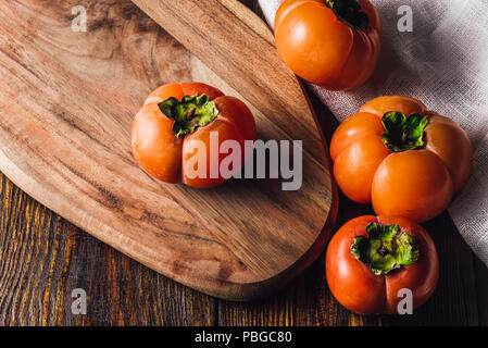 Four Ripe and Sweet Persimmons on Cutting Board Stock Photo