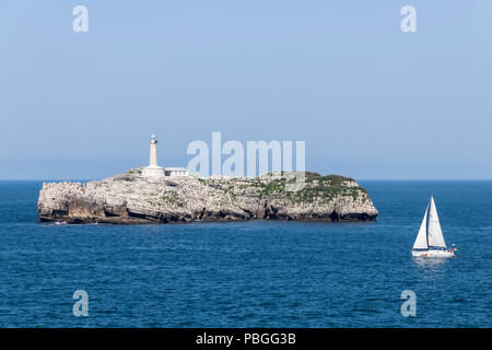 Santander, Spain. Views of the Isla de Mouro (Mouro Island) from the Magdalena Peninsula in Cantabria, with a small sailing ship in the foreground Stock Photo