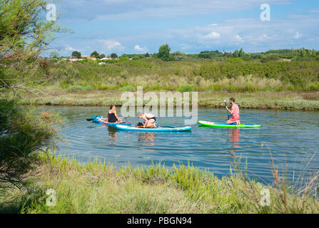 Vendee France, 23 July 2018: three young people enjoying doing stand up paddle on a calm river on hot summer day Stock Photo