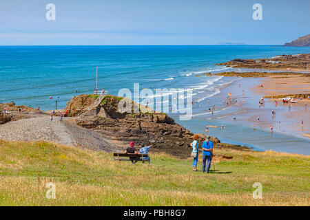 Bude, Cornwall, UK - Tourists on Compass Hill looking down over busy Summerleaze Beach during the summer heatwave, as people cool off in Stock Photo