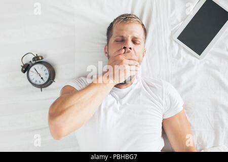 Tired man sleeping on bed after using his digital tablet Stock Photo