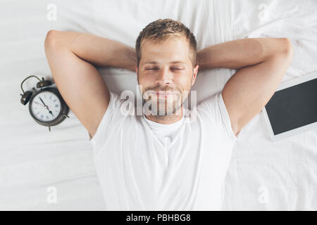 Tired man sleeping on bed after using his digital tablet Stock Photo