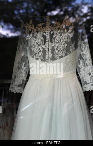 Wedding dress with lace and buttons in shop window Stock Photo