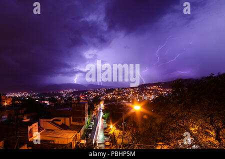 Lighting storm over a city in the night illuminating the night sky Stock Photo