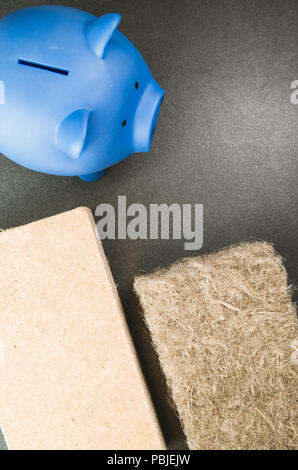 terracotta piggy bank and wall insulation panel on a stone background - top view Stock Photo