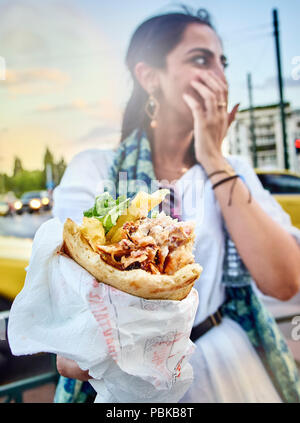 Athens, Greece - June 29, 2018. Greek woman eating a traditional Gyros, set on Pita bread, typical of greek street food. Stock Photo