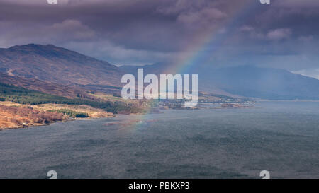 A storm blows through Lochalsh in the Northwest Highlands of Scotland, casting a rainbow across Loch Carron sea loch. Stock Photo