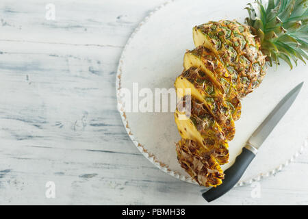 Fresh sliced pineapple on a white wooden cutting board. Top view Stock Photo
