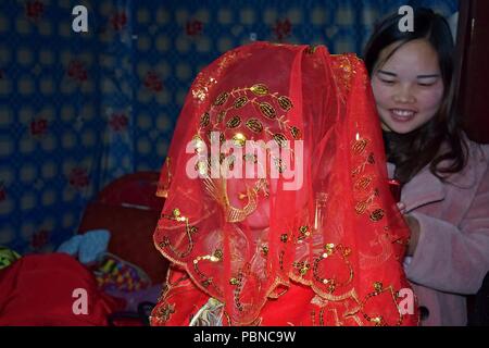 GUIZHOU PROVINCE, CHINA – CIRCA DECEMBER 2017: A wedding, chinese ethnic minority Yao and Shui. A bride covered with red wedding veil. Stock Photo