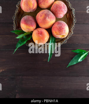 fresh ripe peaches in a round iron plate, top view, copy space Stock Photo