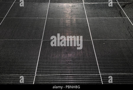 light reflections of early morning sun on metal grid at floor Stock Photo