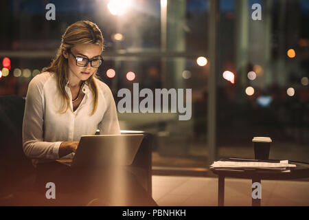Young woman working on the laptop late at night. Caucasian businesswoman working overtime in the office to finish the project within the deadline. Stock Photo