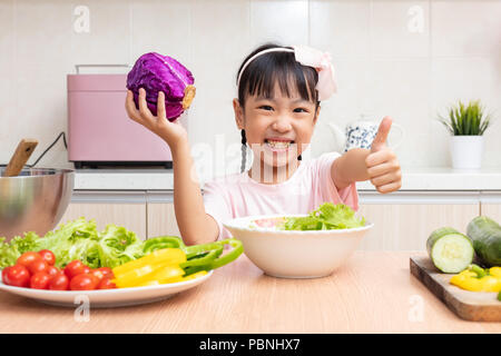 Asian Chinese little girl making salad in the kitchen at home Stock Photo