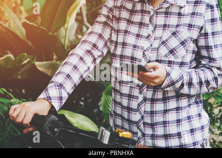 Asian woman holding and using phone on bicycle with vintage toned. Stock Photo