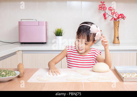 Asian Chinese little girl making dumpling in the kitchen at home Stock Photo