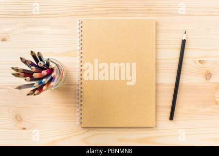 Design concept - Top view of kraft spiral notebook, pen holder and wood pen on wooden table background for mockup Stock Photo