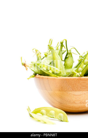 Photo of green pea pods in wooden plate isolated on white background Stock Photo