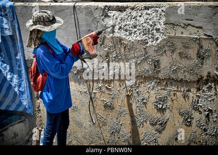 Thailand woman builder. Female construction worker, woman builder drilling concrete wall Stock Photo