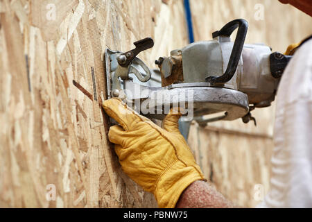 Carpenter cutting an opeing for a window on a new wall using a circular saw Stock Photo