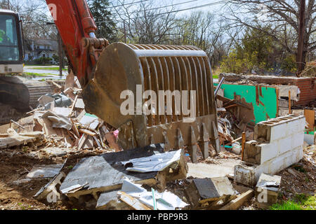 old house being excavator demolished by a large backhoe wooden planks and rubble and the ruins Stock Photo