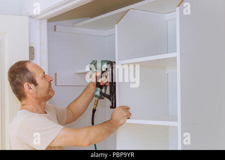 Hanging the shelf onto some wall mounted brackets carpenter worker air gun Stock Photo