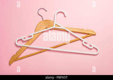 Wooden and plastic clothes hangers isolated and casting shadow on pink background Stock Photo