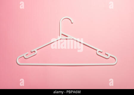 A white plastic clothes hanger isolated and casting shadow on pink background Stock Photo