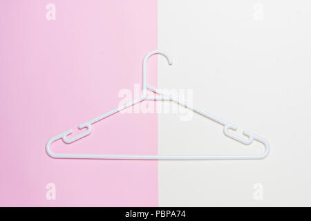 A white plastic clothes hanger isolated on pink and white background Stock Photo