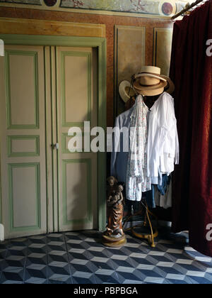 Attractive hallway in large Old French village house with handpainted walls and hat clothes stand Stock Photo