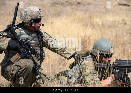 Staff Sgt. Taylor Anderson, Squad Leader, Alpha Co. 3rd Battalion, 161st Infantry Regiment checks on Spc. Jonathan Canfield during a squad tactics exercise lane on July 20, 2018 at Joint Base Lewis-McChord. 3rd Battalion is currently conducting a three-week annual training. (US National Guard photo by Joseph Siemandel) Stock Photo