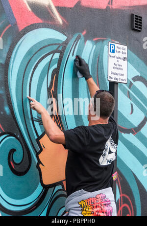 Inkie working on his wall mural at the 10th anniversary of UPFest, the Urban Paint Festival in South Bristol, UK Stock Photo