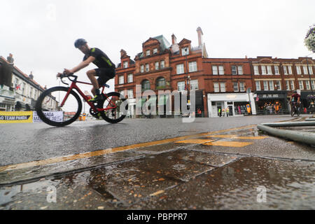 London UK. 29th July 2018. Cyclists  passes through Wimbledon village in the Prudential London Surrey 100 classic event in wet conditions as the rains start to come down. The Prudential Ride London-Surrey 100 in its 6th year celebrates  the legacy for cycling created by the London 2012 Olympic and Paralympic Games and  follows a 100-mile route on closed roads through the capital and into Surrey  countryside Credit: amer ghazzal/Alamy Live News Stock Photo