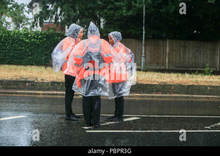 London UK. 29th July 2018. Race stewards dressed in  rain ponchos for the Prudential London Surrey 100 classic event in wet conditions as the rains come down. The Prudential ride Celebrates  the legacy for cycling created by the London 2012 Olympic and Paralympic Games and follows a 100-mile route on closed roads through the capital and into Surrey’s  countryside Credit: amer ghazzal/Alamy Live News Stock Photo