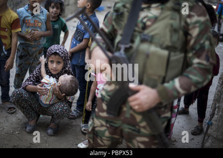 Gaza City, The Gaza Strip, Palestine. 29th July, 2018. Kids seen standing next to an armed soldier.Ayman al-Najjar's funeral in Jabaliya refugee camp in the northern Gaza Strip. He was among two people killed in an Israeli air strike on the east Jabaliya refugee camp near the border with Israel. Credit: Mahmoud Issa/SOPA Images/ZUMA Wire/Alamy Live News Stock Photo