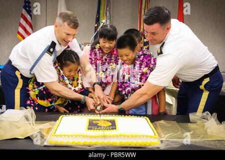 From left, Lt. Col. Matthew D. Lee, commander of the the 2nd Battalion, 27th Infantry Regiment, 3rd Infantry Brigade Combat Team, Schofield Barracks, Hawaii, Nanaho Nakamura, Ayaka Kanzak, Yugen Izuka, 3 children from the orphanage, Battalion Command Sgt. Major Timothy Custis, and in the back is Yuto Nakamura, the 4th child from the orphanage close out the welcome ceremony July 24, at Daniel K. Inouye International Airport, Honolulu, Hawaii by cutting the cake. This marked the beginning of the 61st occurrence of this long-standing tradition that has never ceased, no matter what deployments hav Stock Photo