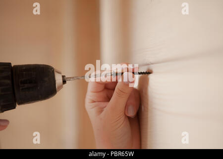 Close-up the woman holding the screw and the electric screw-driver. Stock Photo