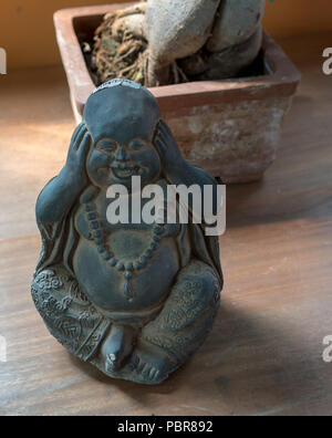 A Buddha or bodhisattva figure laughing with his hand covering his ears Stock Photo