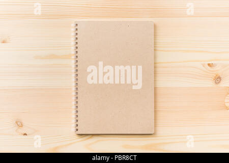 Design concept - Top view of black kraft spiral notebook on wood table background for mockup Stock Photo
