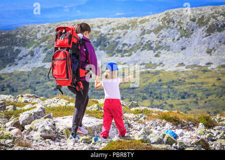 Family walking through rocky landscape. Mother and daughter holding hands. Girl pointing towards new direction. Stock Photo
